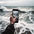 A man photographs a stormy sea on a smartphone, large waves, close-up,