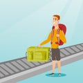 Man picking up suitcase from conveyor belt.