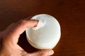 A man picks up white Vaseline to moisturize his skin, dark background