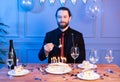 Man with a piece of cake in his hands. For a birthday table. Cake with candles on the table. Royalty Free Stock Photo