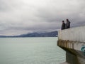 Man on the pier against the backdrop of seagulls. People feed the seagulls. Birds on the sea