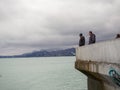 Man on the pier against the backdrop of seagulls. People feed the seagulls. Birds on the sea. Beautiful seascape in cloudy weather