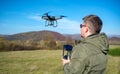 Man pilots a drone in nature by controlling it from a remote control. Royalty Free Stock Photo