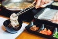 Man pinching boiled well done Kurobuta pork and dipping in ponzu sauce with tong