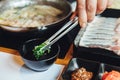 Man pinching minced scallion in ponzu sauce with tong for dipping with Kurobuta pork