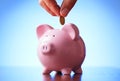 Man placing a coin into a piggy bank