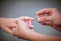 Man placing a diamond engagement ring on finger of his fiance Royalty Free Stock Photo