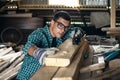 Man in a plaid shirt, goggles and gloves checks the quality of the planed board in the workshop, manual labor, home craftsman