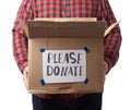 Man in a plaid shirt and jeans holds a brown cardboard box with the inscription please donate Royalty Free Stock Photo