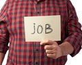 Man in a plaid shirt and jeans holds a piece of paper with the inscription job, unemployment concept against the backdrop of the Royalty Free Stock Photo