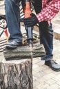 Man in plaid shirt sawing piece of wood on stump Royalty Free Stock Photo