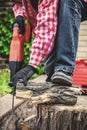 Man in plaid shirt sawing piece of wood on stump Royalty Free Stock Photo