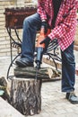 Man in plaid shirt sawing piece of wood on stump Royalty Free Stock Photo