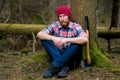 Man in a plaid shirt sitting near a tree in the forest, forester Royalty Free Stock Photo