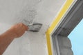 Man plastering window area with putty knife, closeup. Interior repair