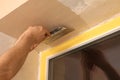 Man plastering window area with putty knife indoors. Interior repair