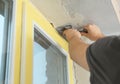 Man plastering window area with putty knife indoors. Interior repair