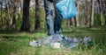 A man with a plastic bag collects garbage in the forest by Impale it on a stick