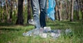 A man with a plastic bag collects garbage in the forest by Impale it on a stick