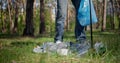 A man with a plastic bag collects garbage in the forest by Impale it on a stick