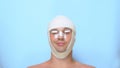 A man after a plastic surgery facelift, rhinoplasty, blepharoplasty. with a bandage on the nose, head and eyes. on blue