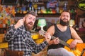 Man play guitar in pub. Live music concert. Acoustic performance in pub. Hipster brutal bearded with friend in pub Royalty Free Stock Photo