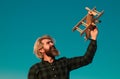 Man play with toy plane. Bearded crazy man with a wooden airplane. Dreams of flying. Travel concept.