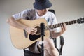 Man playing acoustic guitar through front microphone.