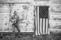 Man playing acoustic guitar standing on front of American flag hanging on old barn door Royalty Free Stock Photo