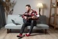 Man playing acoustic guitar watching online lesson on laptop while practicing at home. Online training, online music Royalty Free Stock Photo