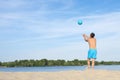 A man playing beach volleyball on hot sand on a sunny day. Back view. Sports lifestyle