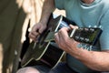 Man playing classical acoustic guitar sitting near tent outdoors. Closeup of hands. Selective focus. Summer concept Royalty Free Stock Photo