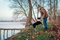 Man playing with dog in autumn park by lake. Happy pet having fun jumping outdoors with its owner Royalty Free Stock Photo