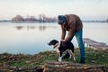 Man playing with dog in autumn park by lake. Happy pet having fun walking outdoors Royalty Free Stock Photo