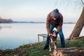 Man playing with dog in autumn park by lake. Happy pet having fun walking outdoors Royalty Free Stock Photo