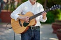 Man playing electro acoustic guitar at outdoor event, free musical performance of street musician