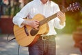 Man playing electro acoustic guitar at outdoor event, free musical performance of street musician