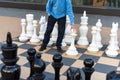 Man playing gigantic chess outdoors. Outdoor chess board with big plastic pieces. Giant size chess in public area zone. Close up Royalty Free Stock Photo