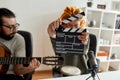 Man playing guitar and woman holding clapperboard. Couple of musicians recording video blog or vlog while making music