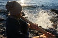 Man playing on Indian Bansuri instrument in sunshine at sea shore