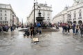 People listen to live music at underground station `Picadilly Circus` on rainy day, London, UK