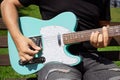 Man playing a turquoise electric guitar in a park on a sunny day Royalty Free Stock Photo