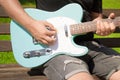 Man playing a turquoise electric guitar in a park on a sunny day Royalty Free Stock Photo