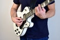 Man playing a white electric guitar with humbucker pickups.