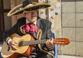 Man plays acoustic guitar while dressed in traditional Mariachi suit