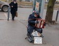 A man plays the button accordion on the street in winter. The inscription in Ukrainian For the treatment of the granddaughter,