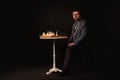 A man plays chess and smokes a pipe on a dark background