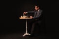 A man plays chess and smokes a pipe on a dark background