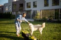 Man plays with a dog while moving lawn at backyard Royalty Free Stock Photo