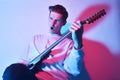 A man plays the electric guitar in neon light, red blue light. Hobbies, music, club. A man enjoys playing the guitar, screaming, Royalty Free Stock Photo